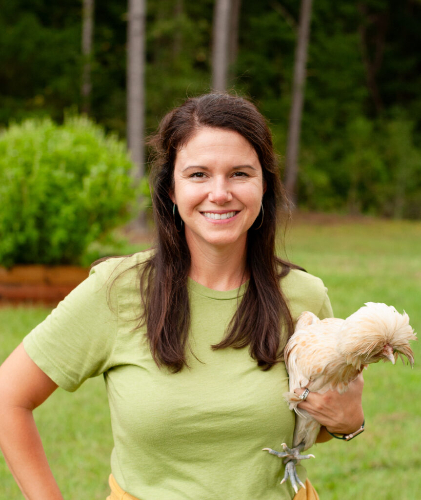 Girl wearing green shirt holding chicken. 