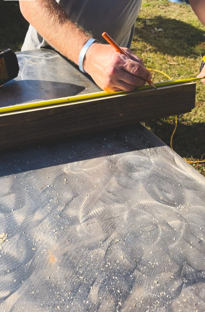 Man measuring wood for a chicken ladder and marking it with a pencil.