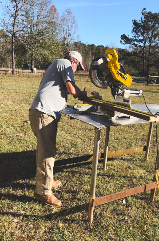 man measuring and cutting wood using a a table saw. 