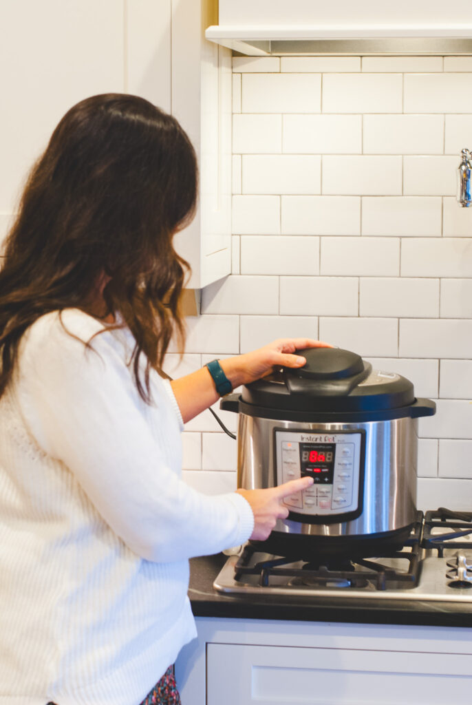 Girl in homestead kitchen wearing white shirt and pressing button on instant pot 