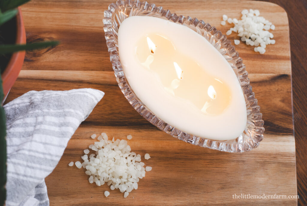 beeswax candle with beeswax pellets on wood surface 