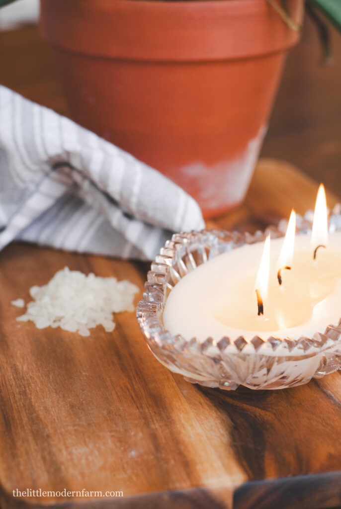 Candles on a wooden surface with beeswax pellets in background 
