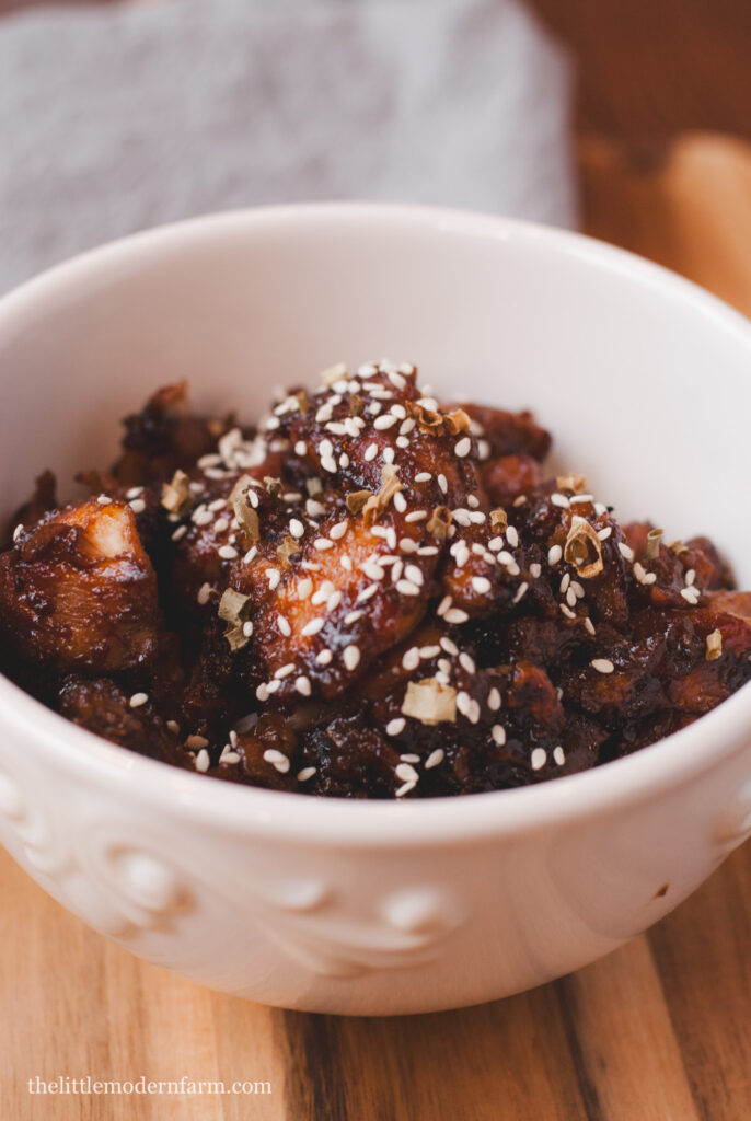 Honey Wine Chicken in white bowl on with gray towel in background. 