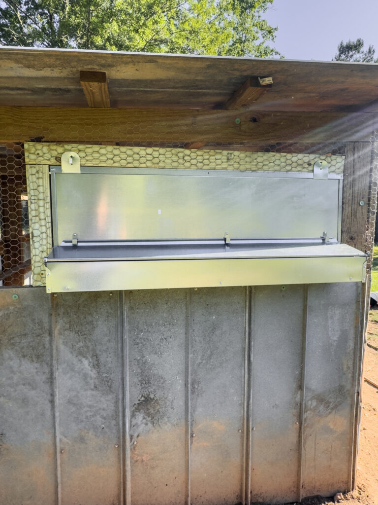 Metal nesting box with exterior egg collection chamber in a coop 