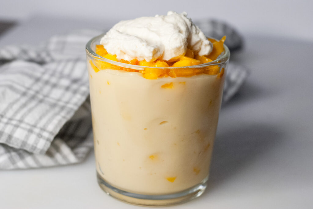 peaches and cream in a class on a counter top. 