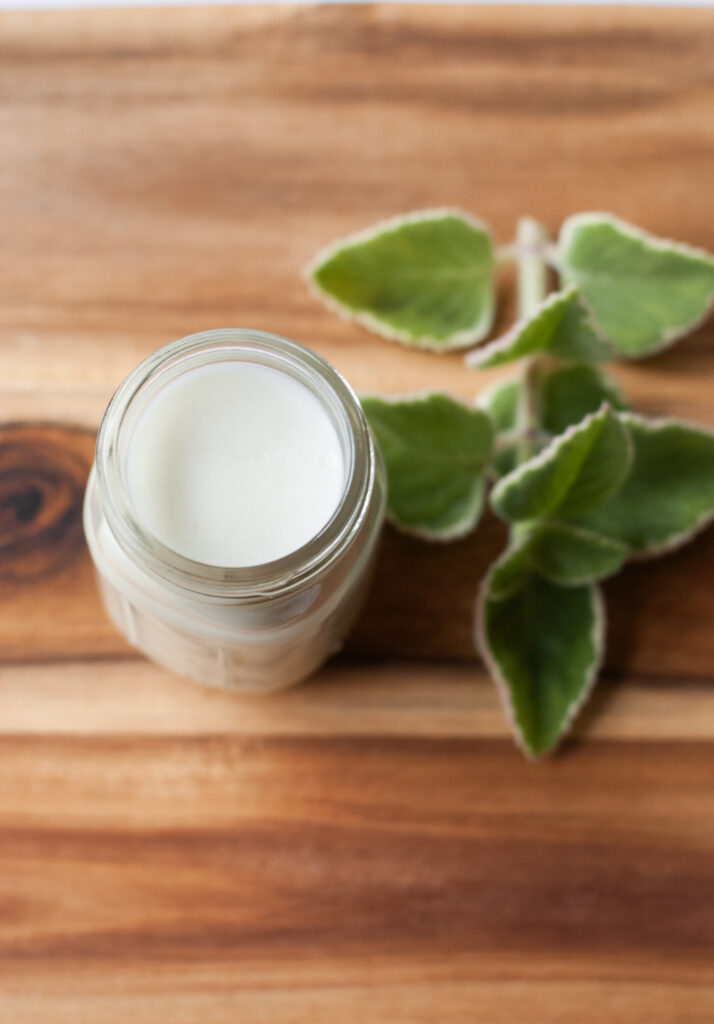 glass jar containing whipped lotions on a wooden surface 