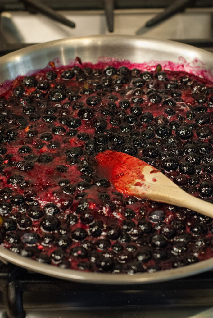 blueberries simmering in a pan on the stove 