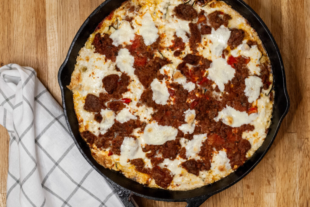 Lasagna with vegetables in a cast iron skillet on a wooden surface 