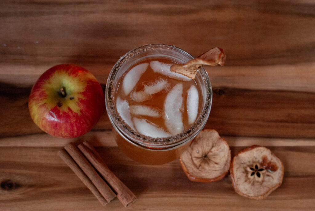 cocktail on table top with apples with and cinnamon stick 