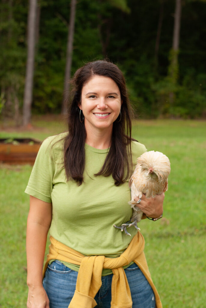 Woman with green shift holding polish chickens with green grass 