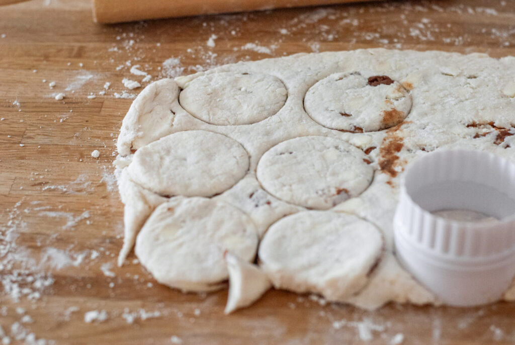 biscuit dough with biscuits cut out on floured surface with biscuit cutter 