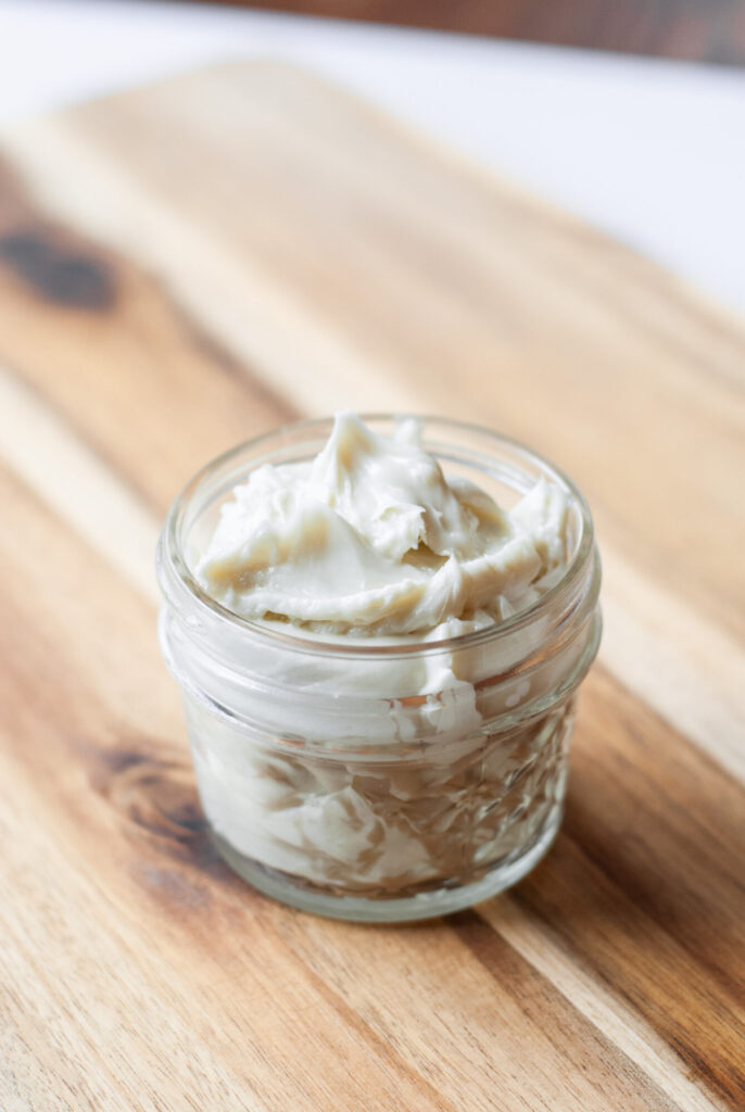 Whipped magnesium lotion in a glass container on a wooden top 