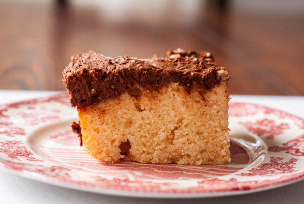 Yellow cake with chocolate frosting on red plate. 