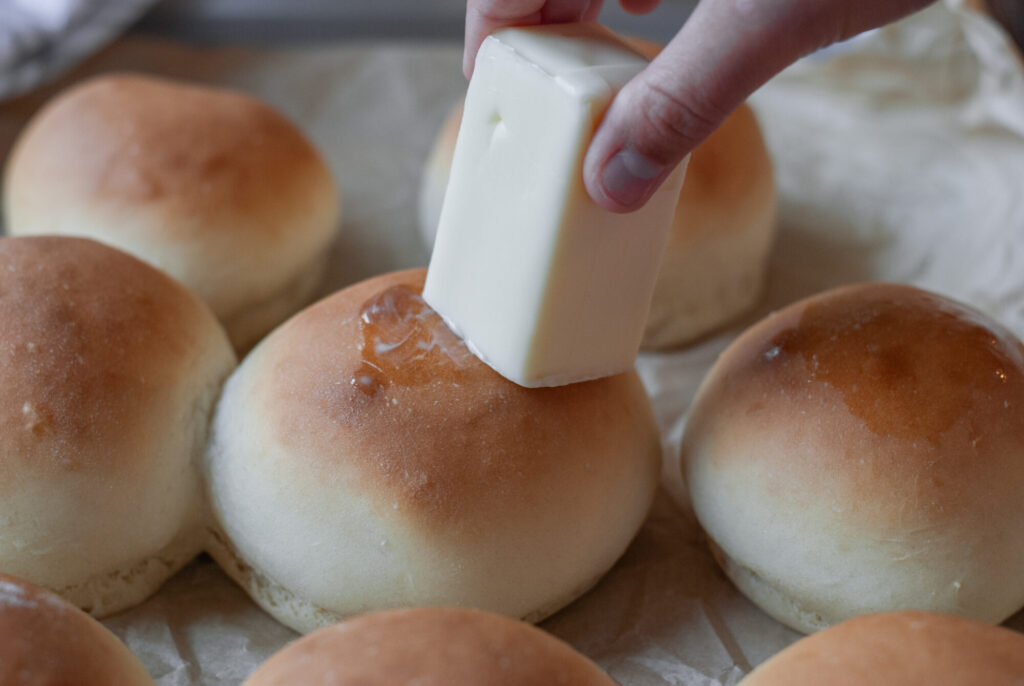 butter being spread on hamburger buns