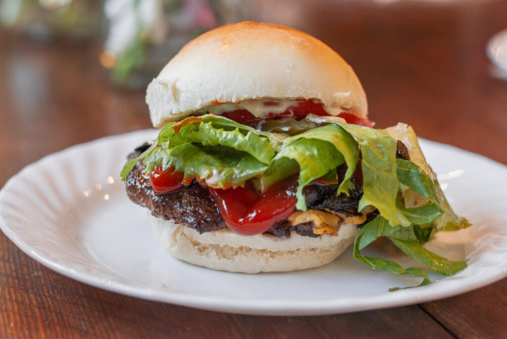 hamburger on a white plate with lettuce and ketchup