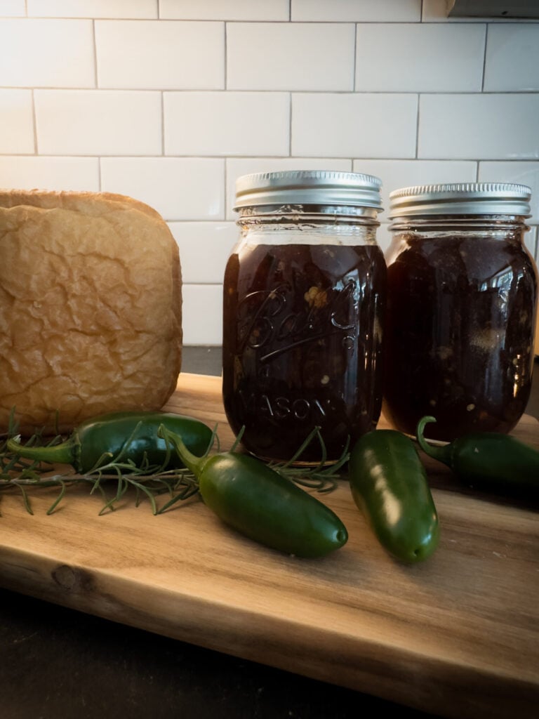 Muscadine jalapeno Rosemary preserves in a jar next to bread