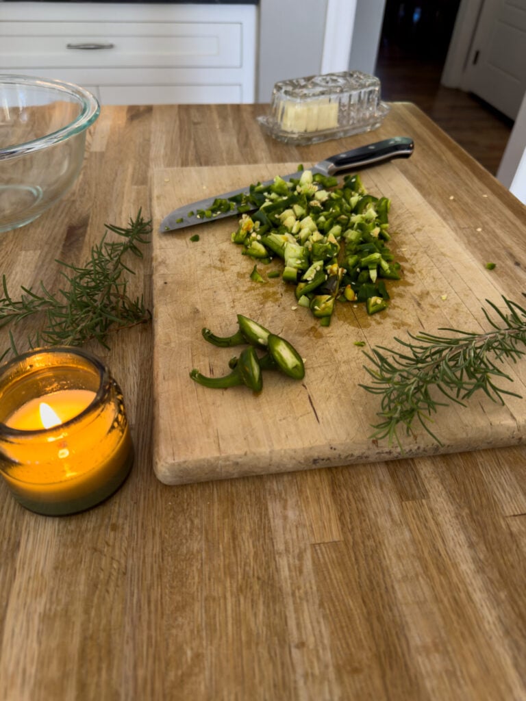 Jalapeno and rosemary on a cutting board next to a candle